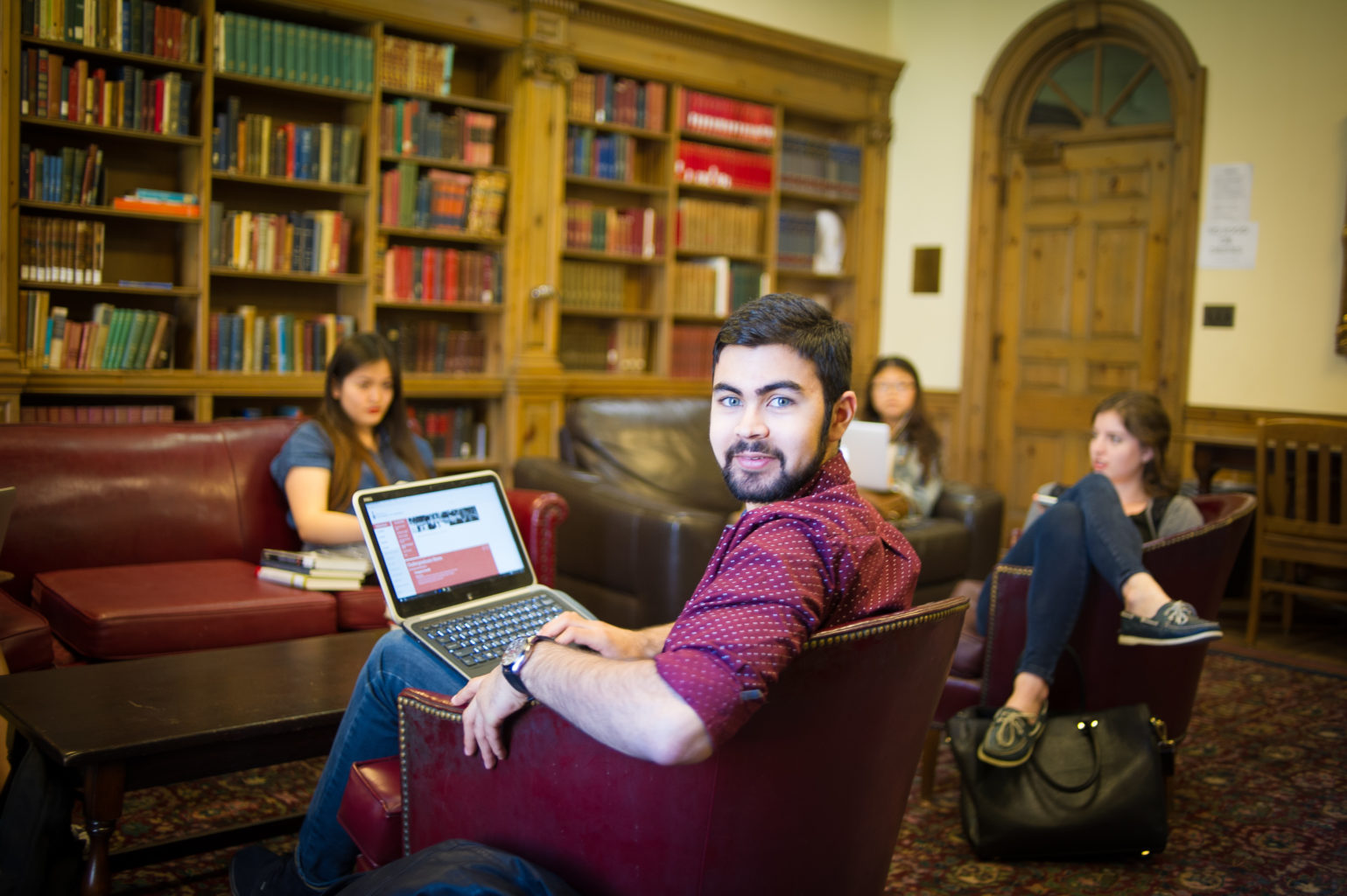 Student looks at the camera while other students are studying in the Stedman Library in St. Hilda's College
